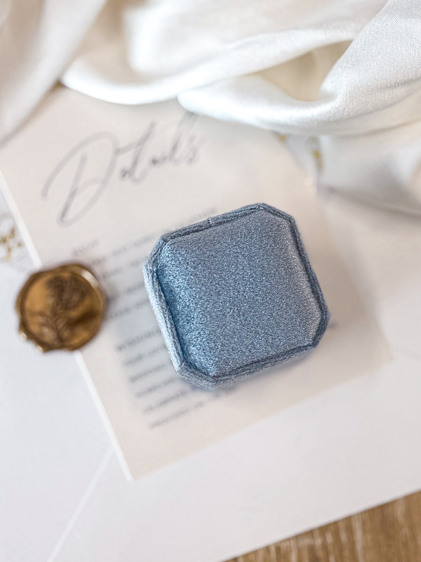 blue VELVET RING BOX CLOSED on a textured surface with a white background