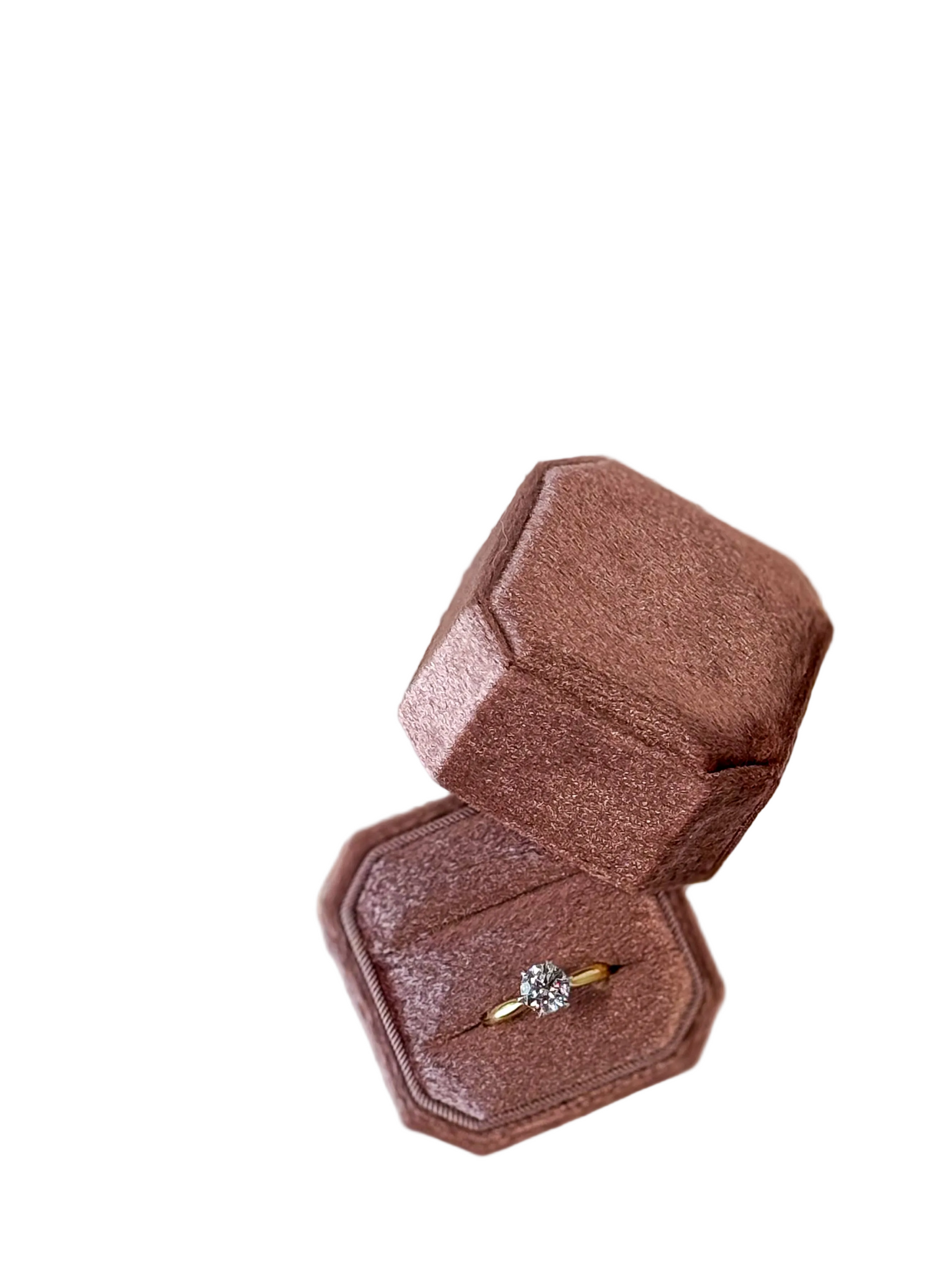 Hexagonal rose gold ring box with a diamond ring on a white surface with text and flowers.