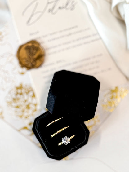 Gold ring with diamond in a black box on a decorative surface