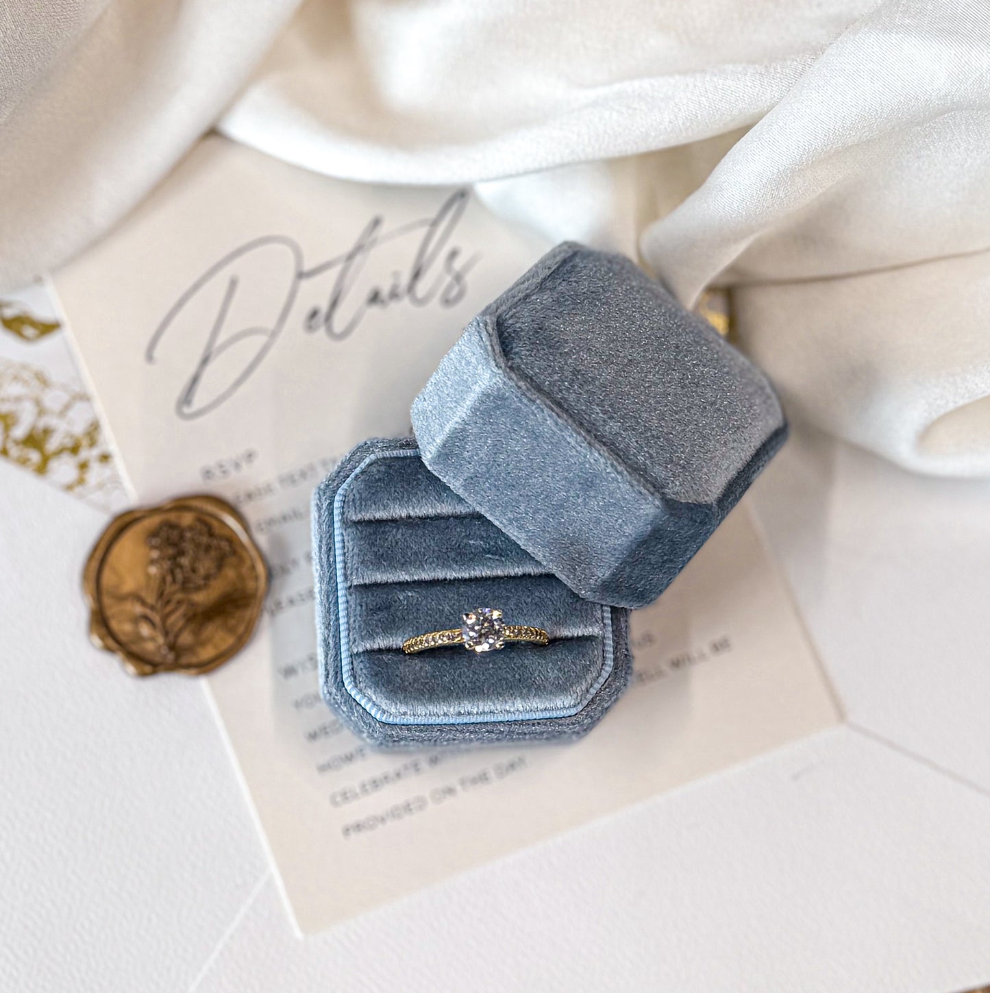 Blue velvet ring box with a ring on a textured surface