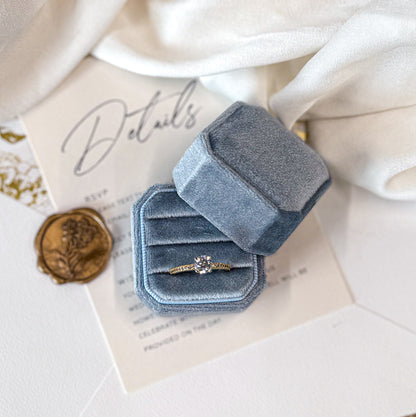 Blue velvet ring box with a ring on a textured surface
