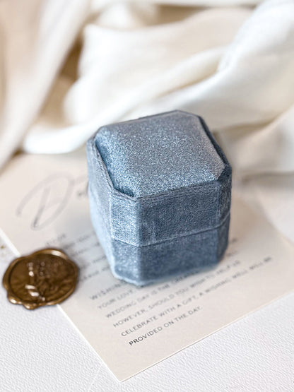 Blue velvet jewelry box on a white surface with a wax seal