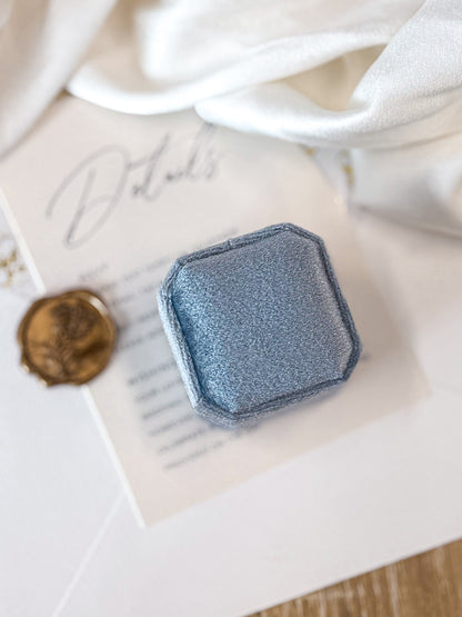 blue VELVET RING BOX CLOSED on a textured surface with a white background