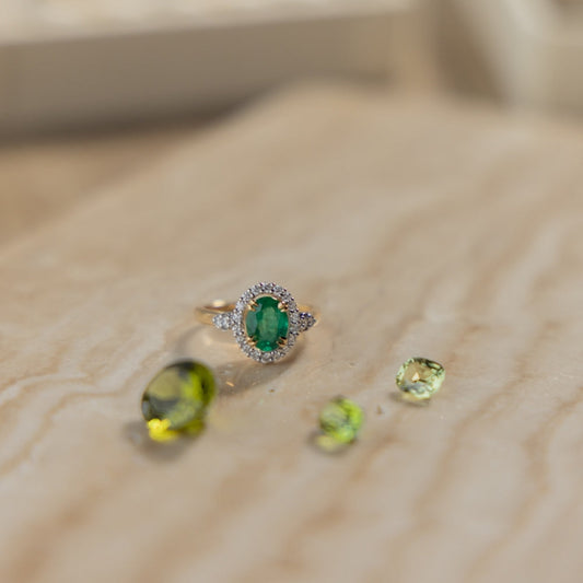emerald diamond ring green loose gemstones on travertine display 