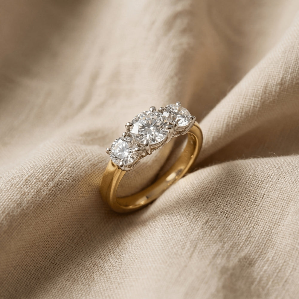 Gold ring with three diamonds on a beige fabric background